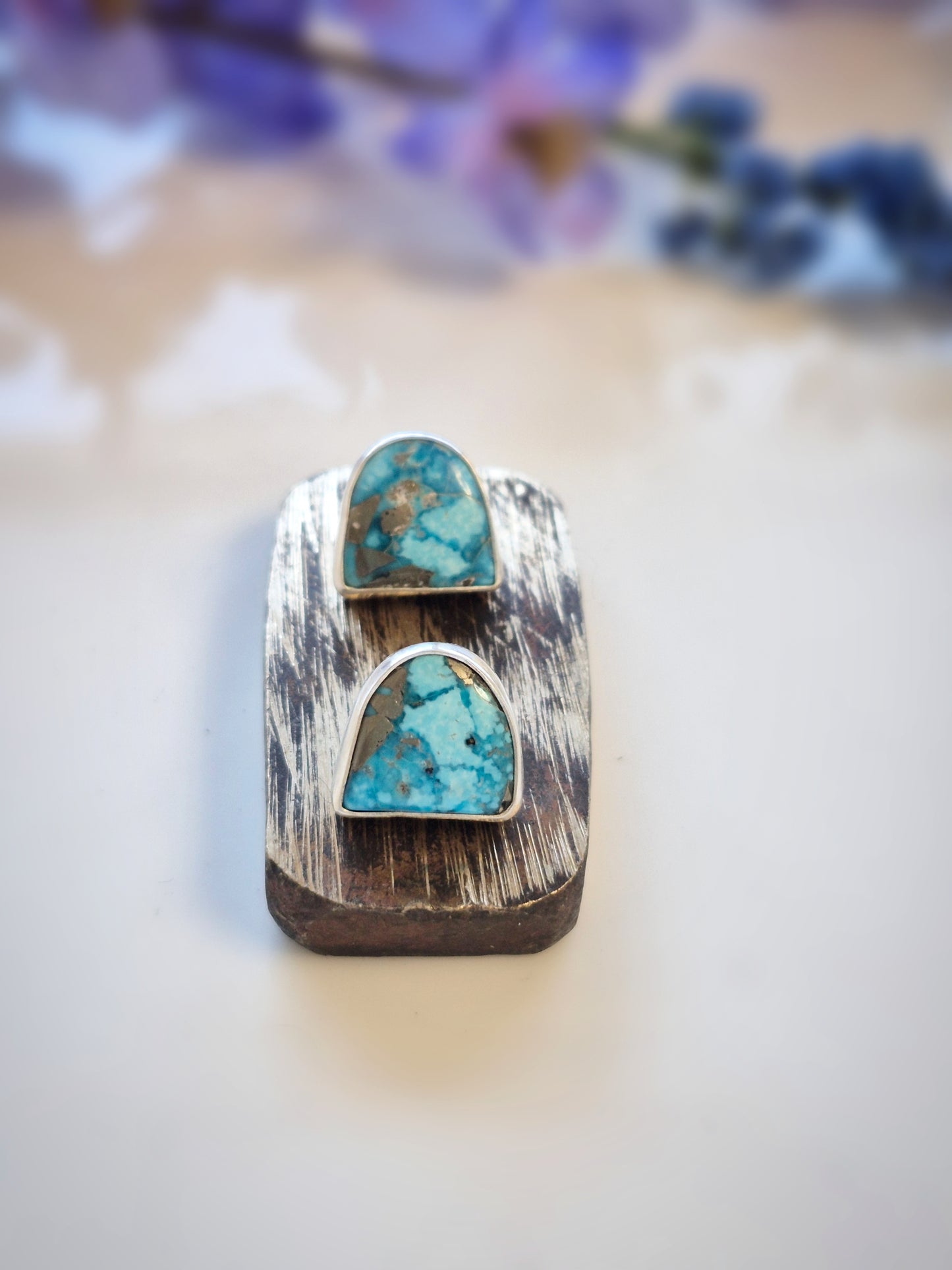 Turquoise stone ring on a wooden surface with a blurred floral background