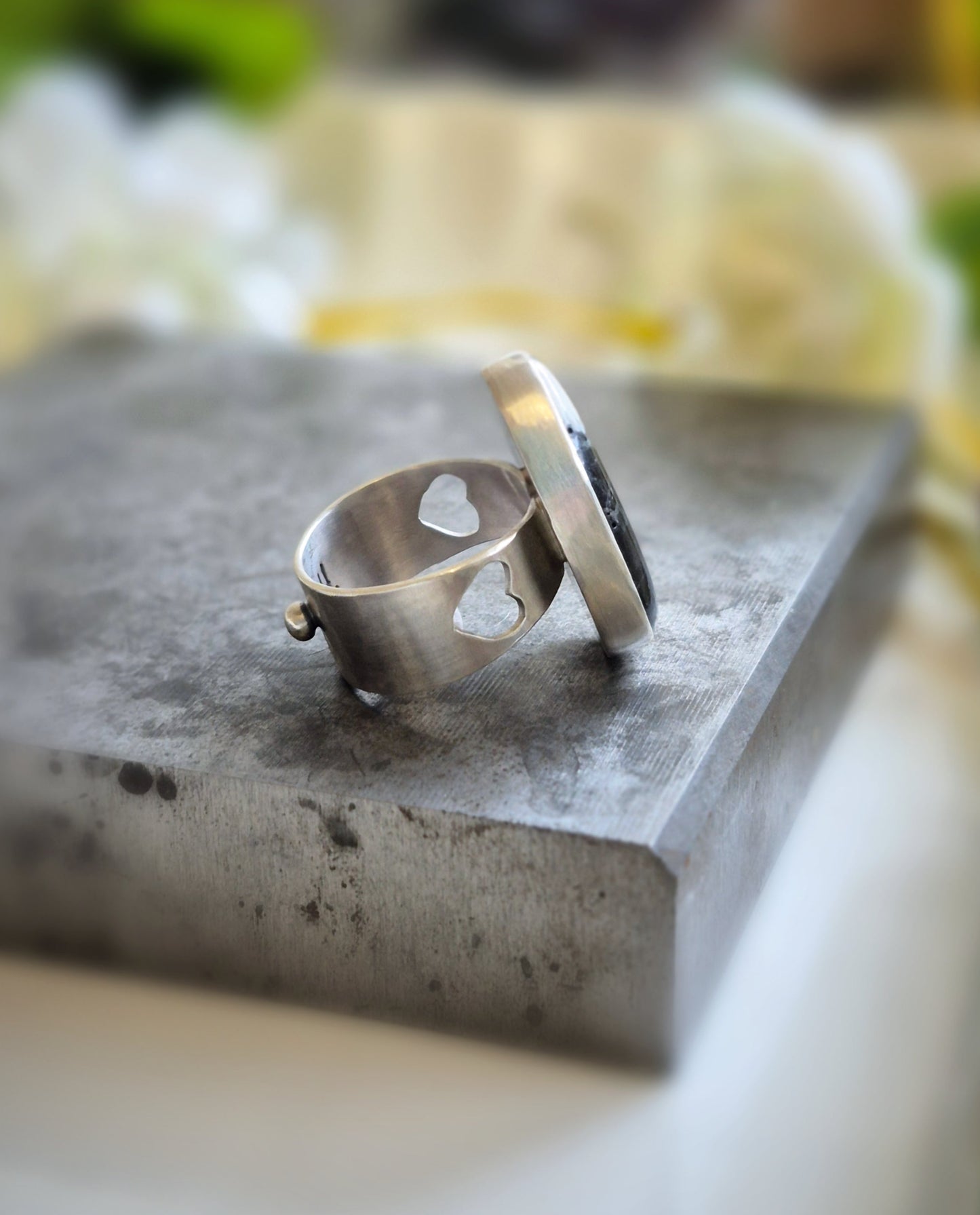 Silver ring on a textured stone surface with a blurred natural background