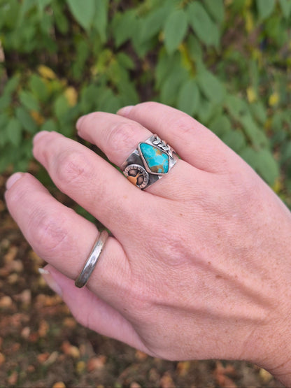 Hand wearing two rings with a natural background