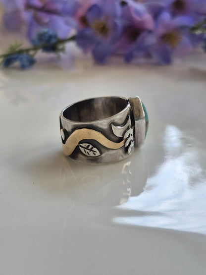 Silver ring with a unique design on a white surface with purple flowers in the background