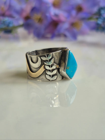 Silver tuquoise ring with accented band design on a white background with purple flowers.