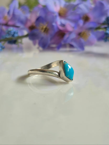 Silver ring with a blue stone against a floral background