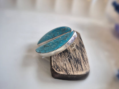 Turquoise earrings on a wooden block with blurred background