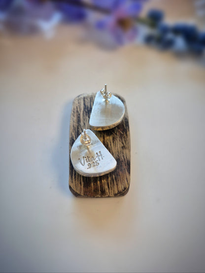 Pair of earrings on a wooden stand with a blurred floral background