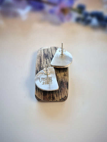 Wooden earring display with silver crescent-shaped earrings on a light background