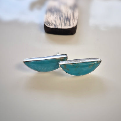 Silver turquoise earrings on a light surface with blurred background