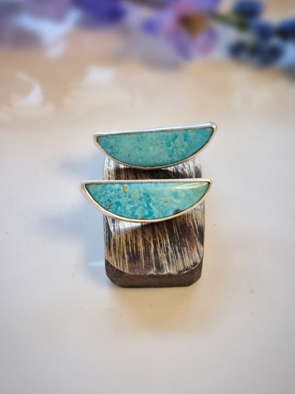 Earrings with turquoise gemstones and silver band on a light background