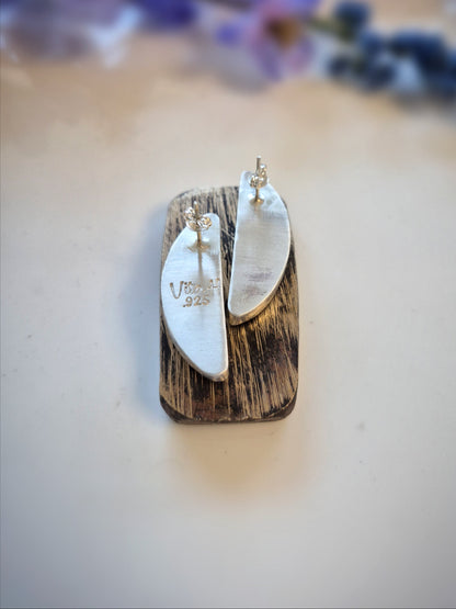 Pair of earrings on a wooden stand with a blurred floral background