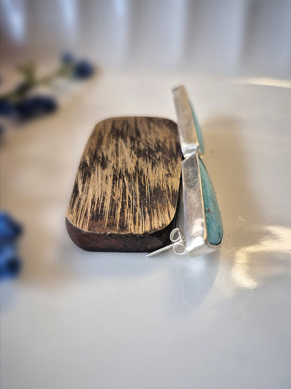 Wooden platform with a silver earrings on a white surface
