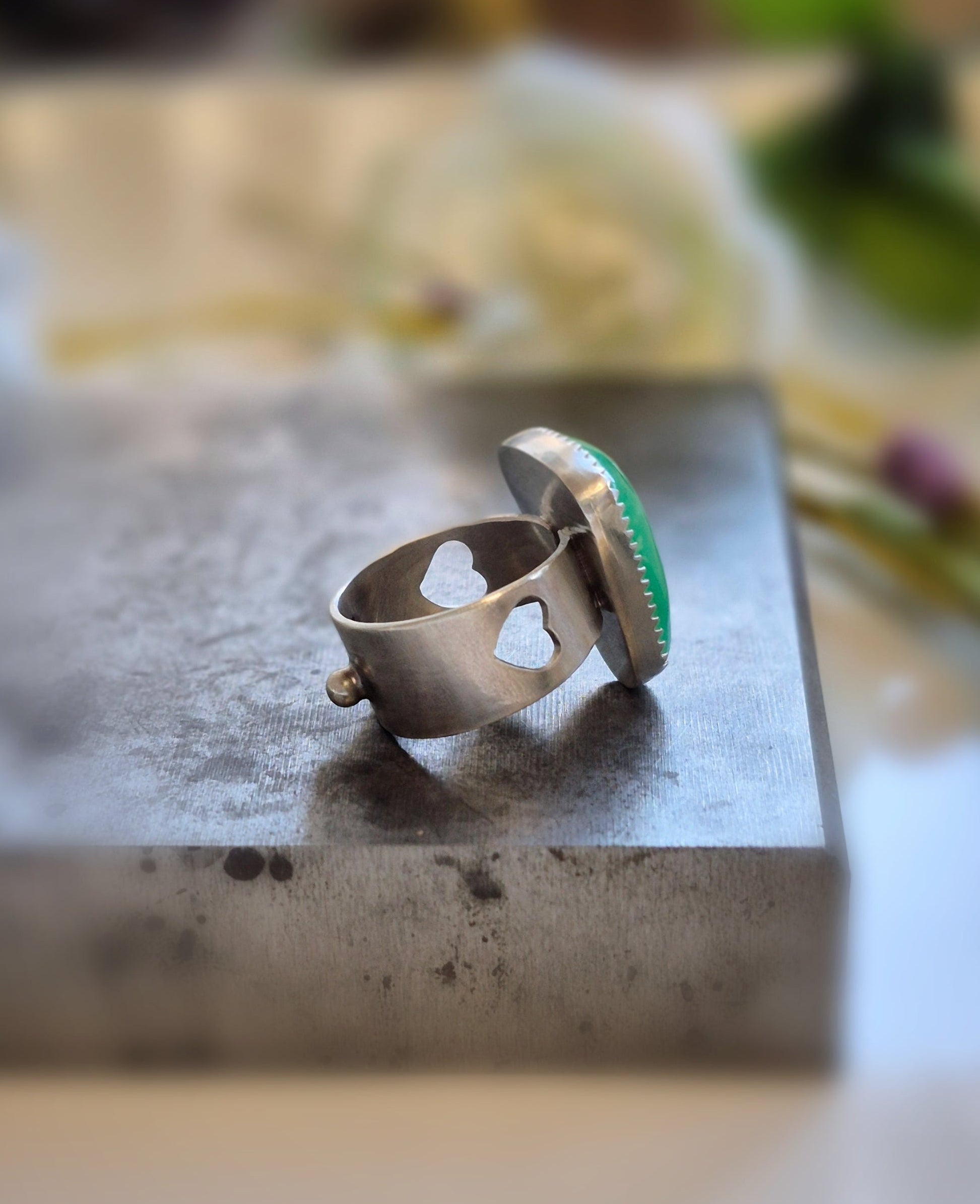 Silver ring with green gemstone on a stone surface