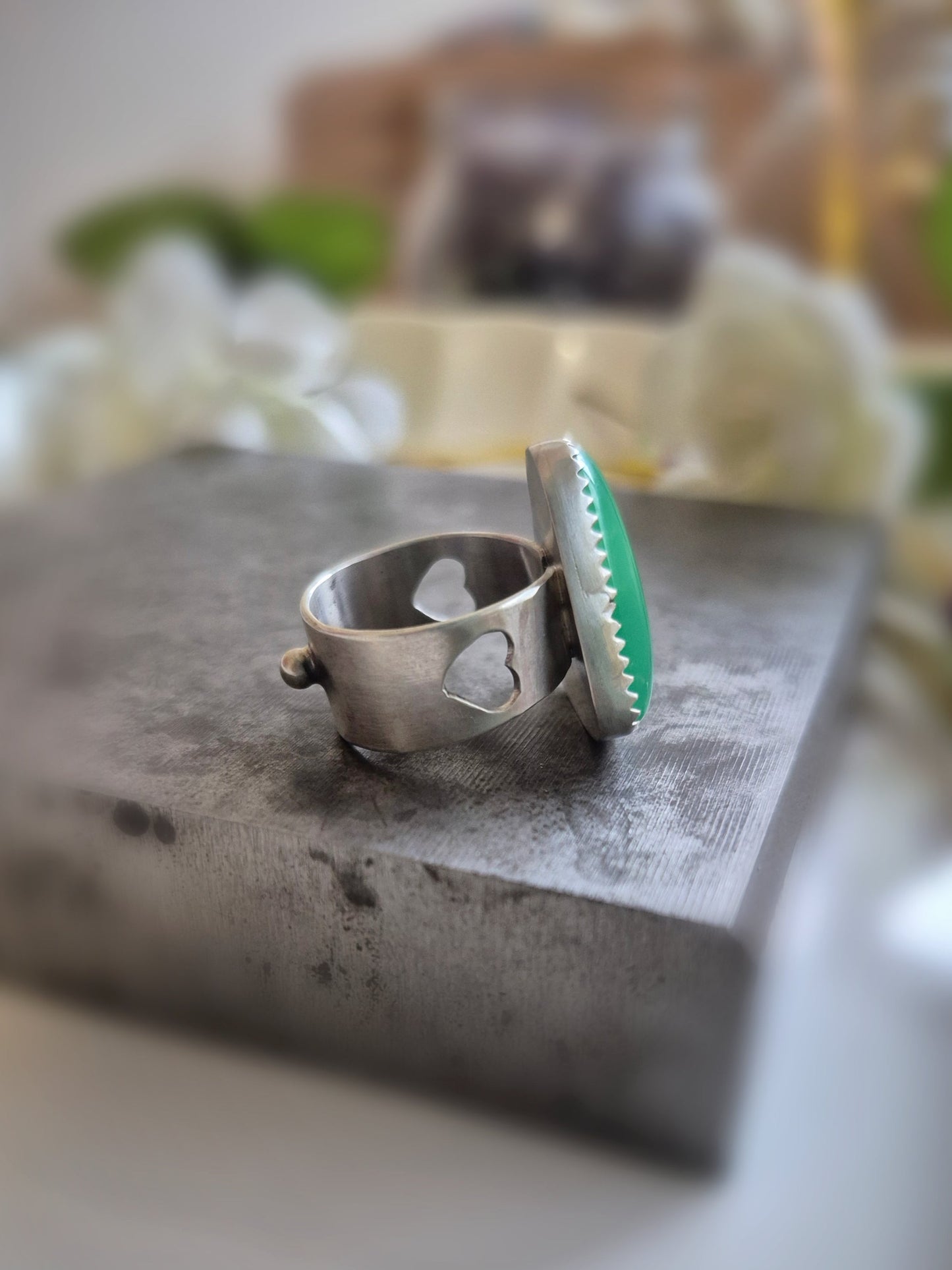 Silver ring with green chrysoprase gemstone on a stone surface