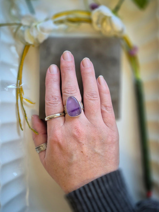 Hand wearing a purple amethyst ring with a blurred background
