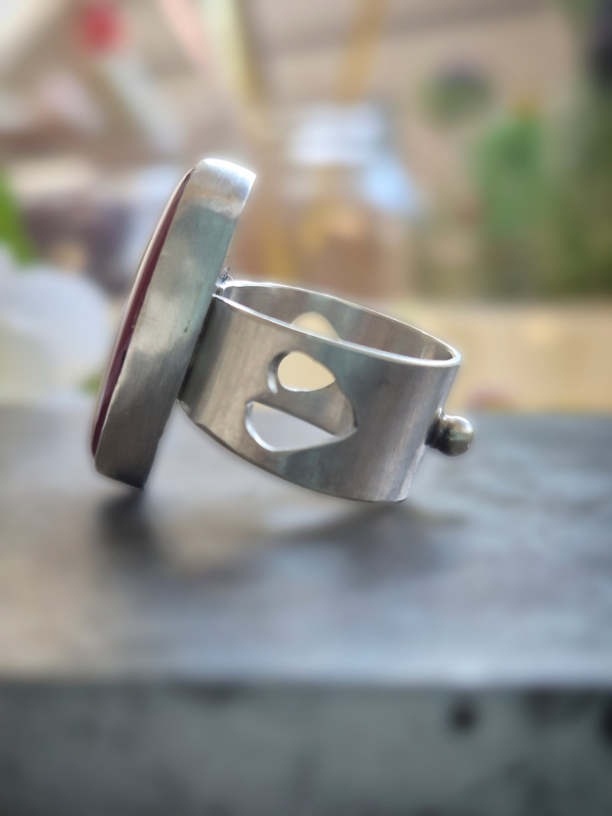 Silver ring with a heart cutout on a dark surface