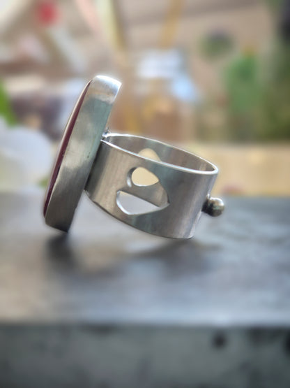 Silver ring with a heart cutout on a dark surface