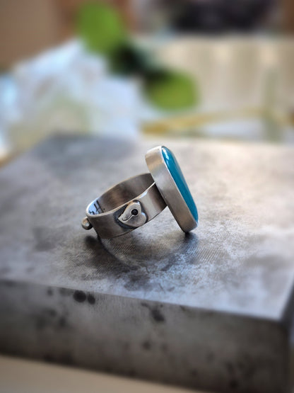 Silver ring with a blue gem silica gemstone on a textured surface
