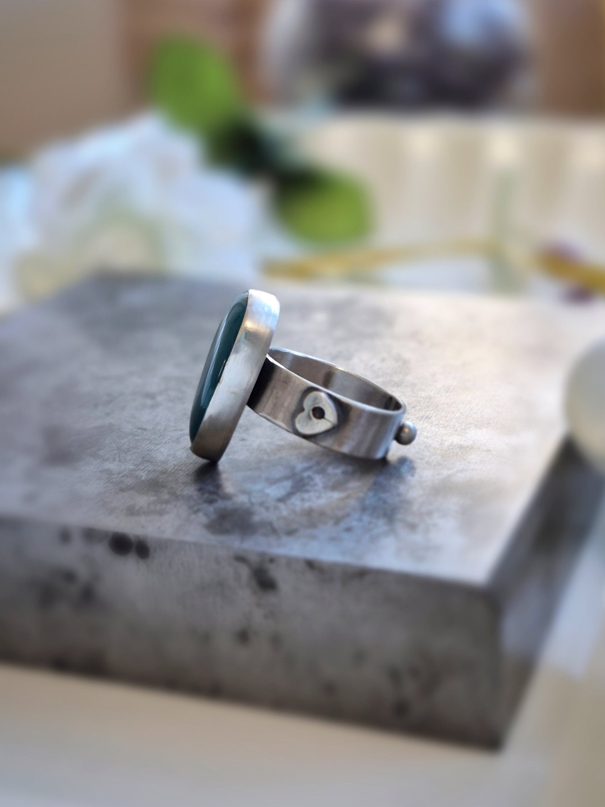 Silver ring with a heart design on a stone surface