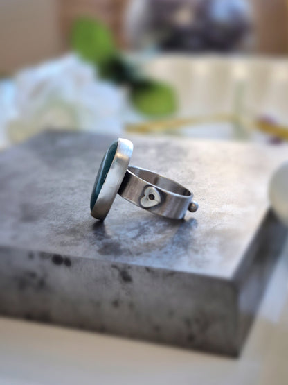 Silver ring with a heart design on a stone surface