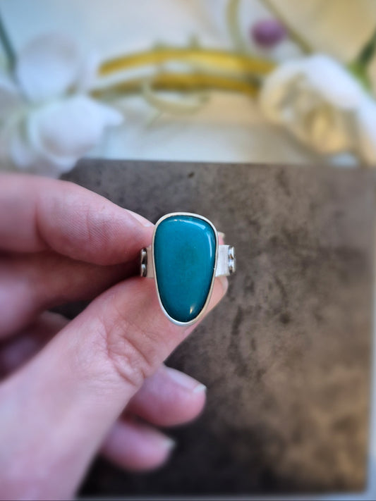 Gem silica ring held by a hand with a blurred floral background