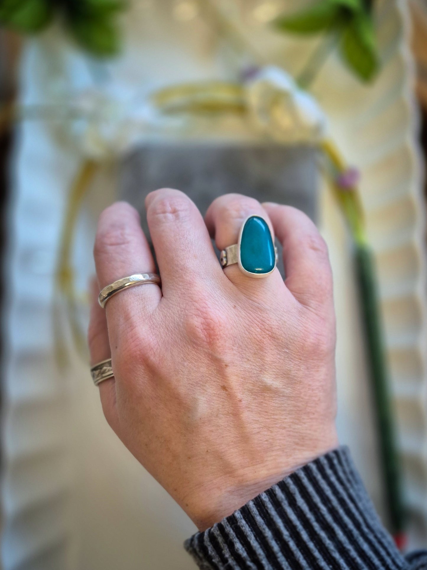 Hand wearing a blue gem silica ring with a blurred background