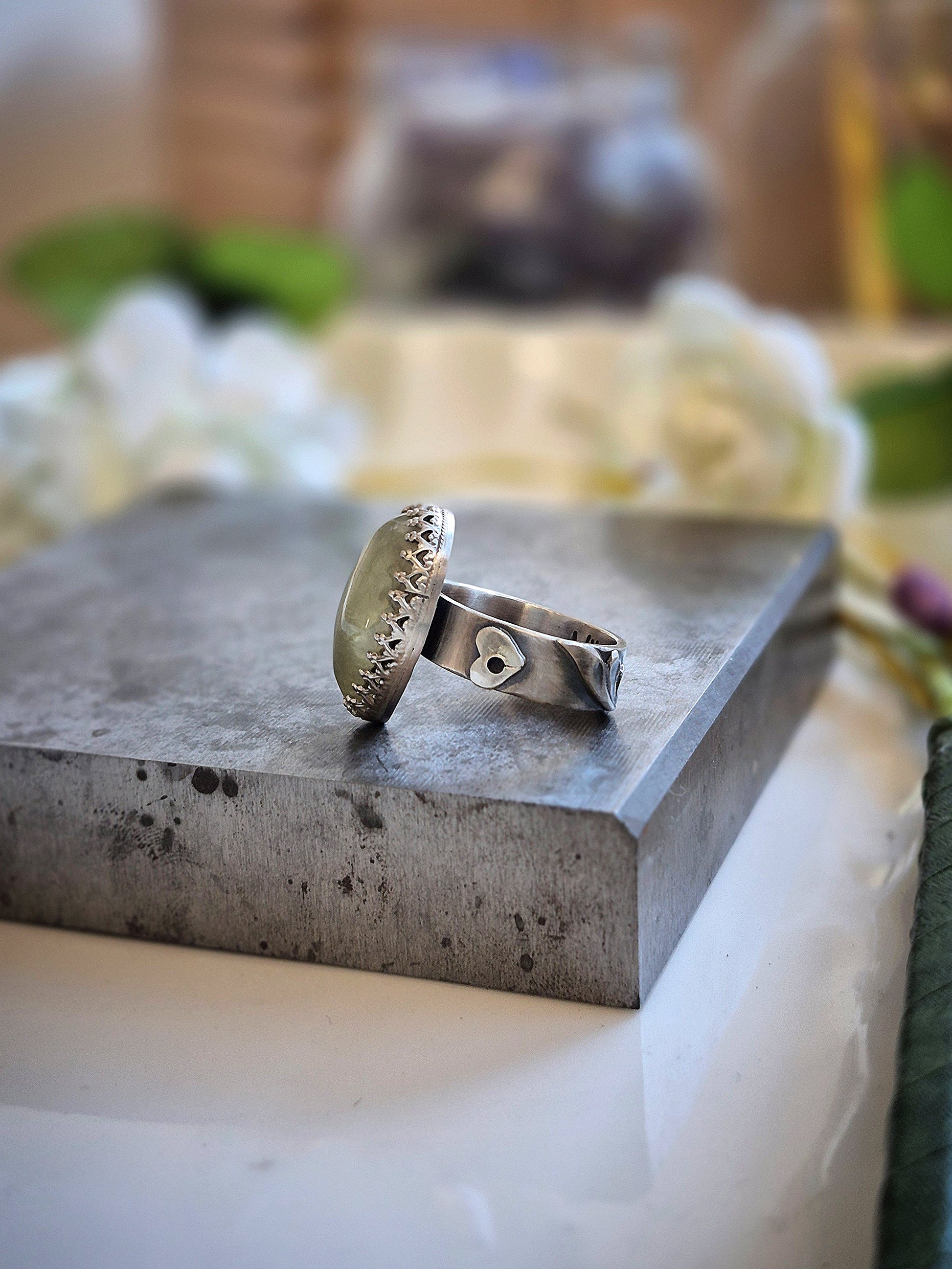 Silver ring on a textured stone surface with a blurred natural background