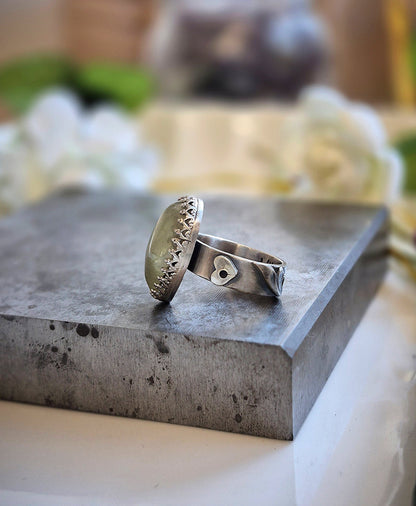 Silver ring on a textured stone surface with a blurred natural background