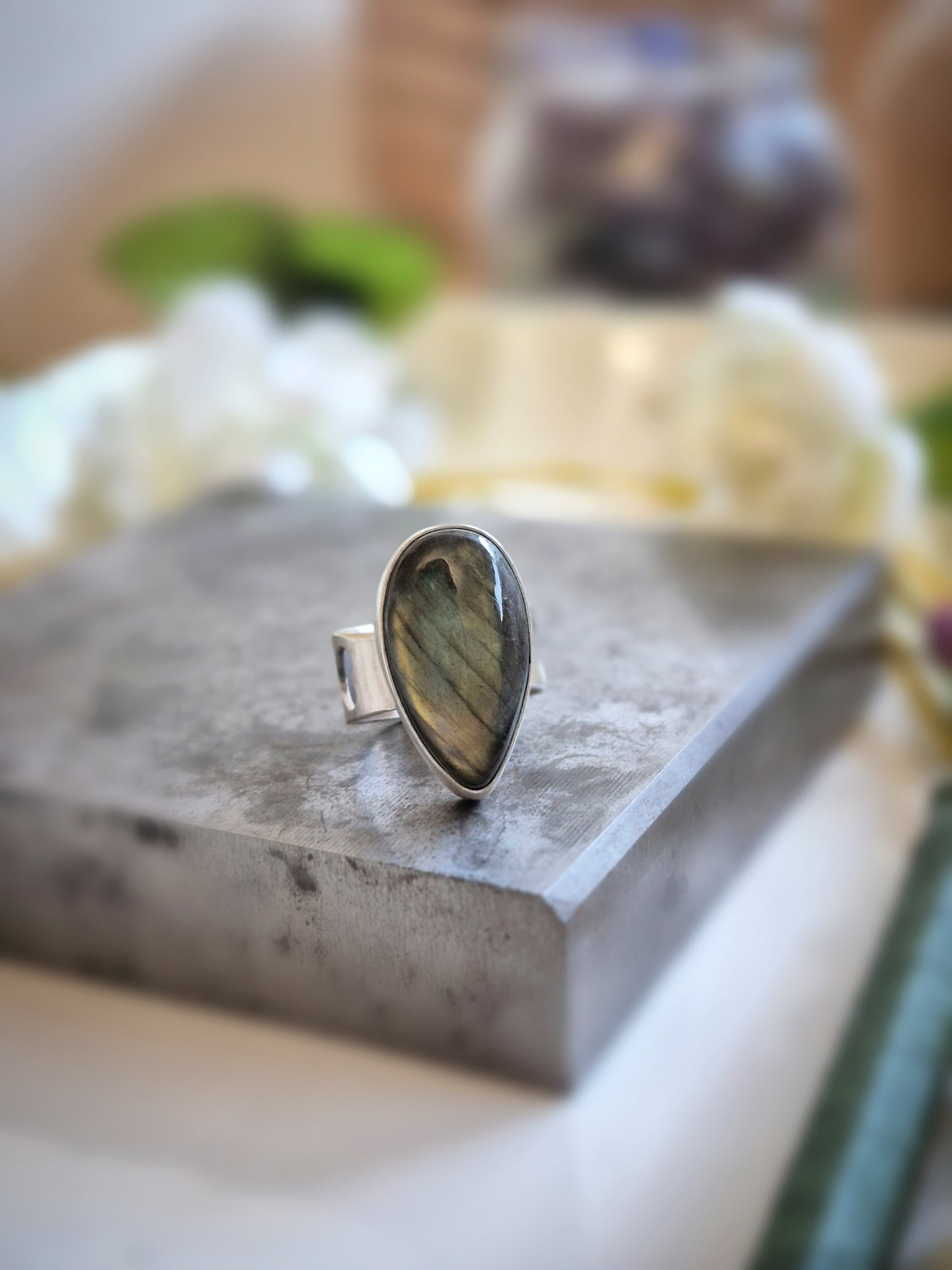 Silver ring with a labradorite stone on a concrete surface