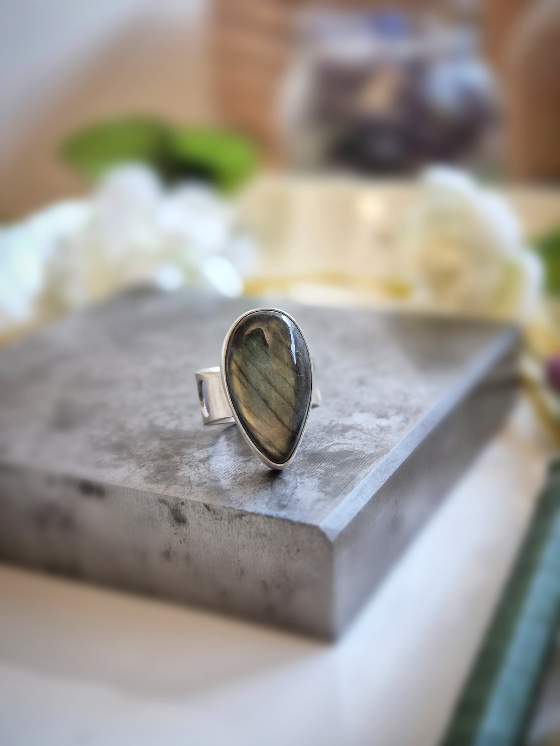 Silver ring with a labradorite stone on a concrete surface