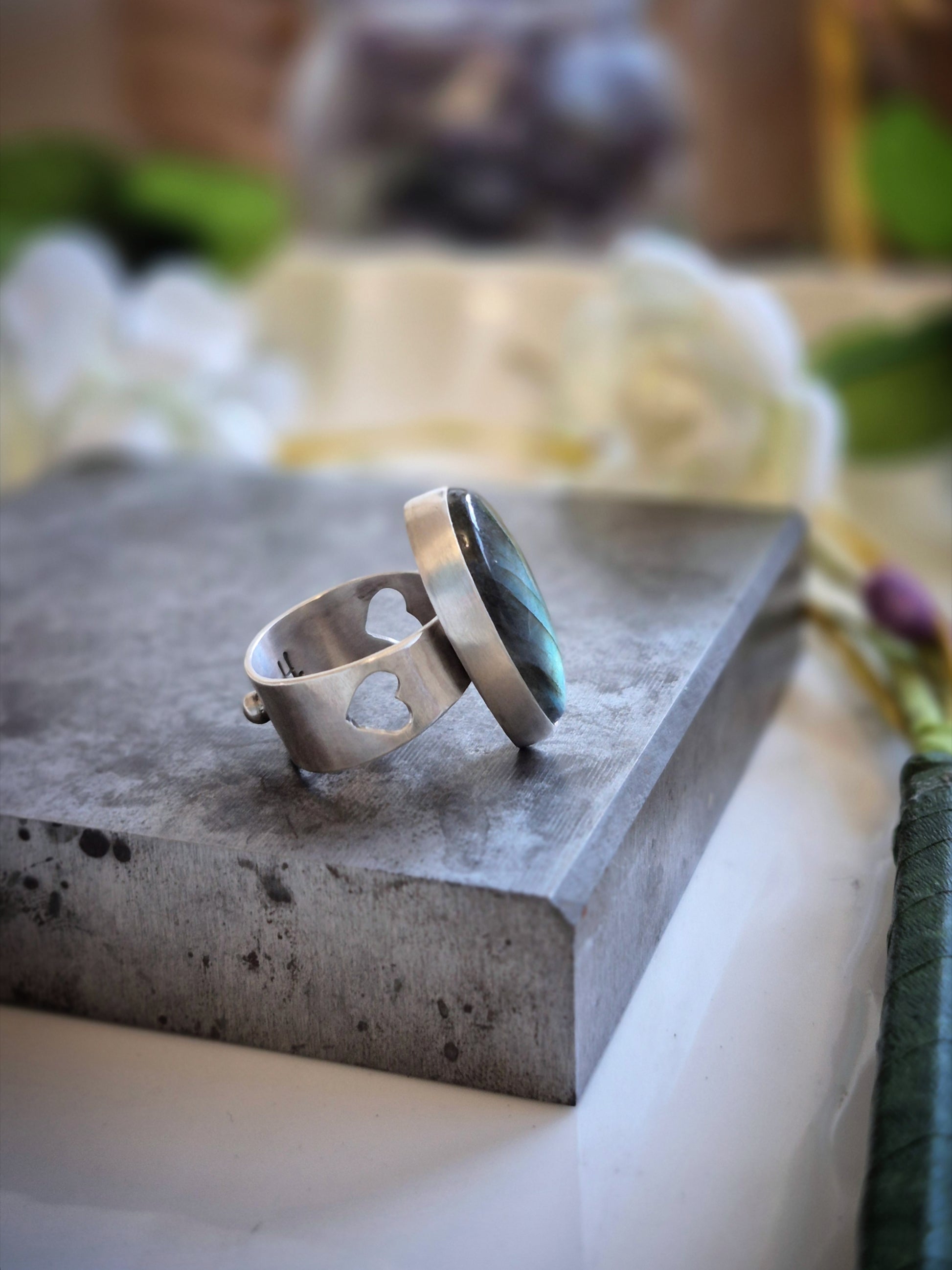 Silver ring with a labradorite stone on a concrete surface