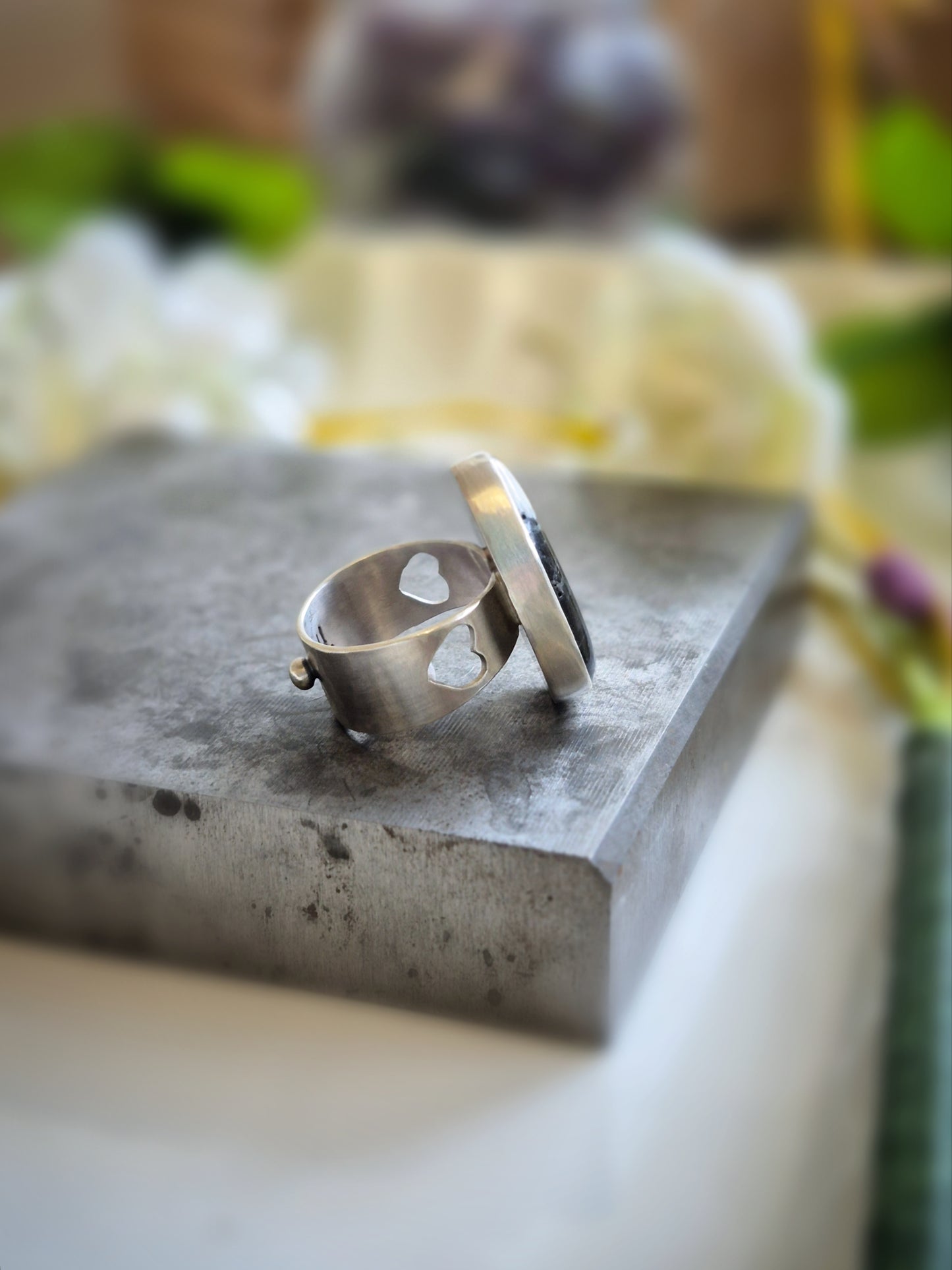 Silver ring on a textured stone surface with a blurred natural background