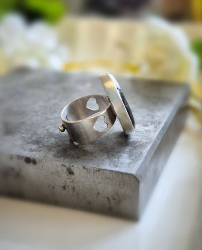 Silver ring on a textured stone surface with a blurred natural background