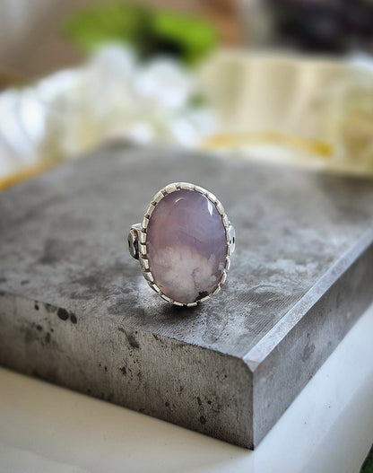 Silver ring with a purple agate stone on a concrete surface