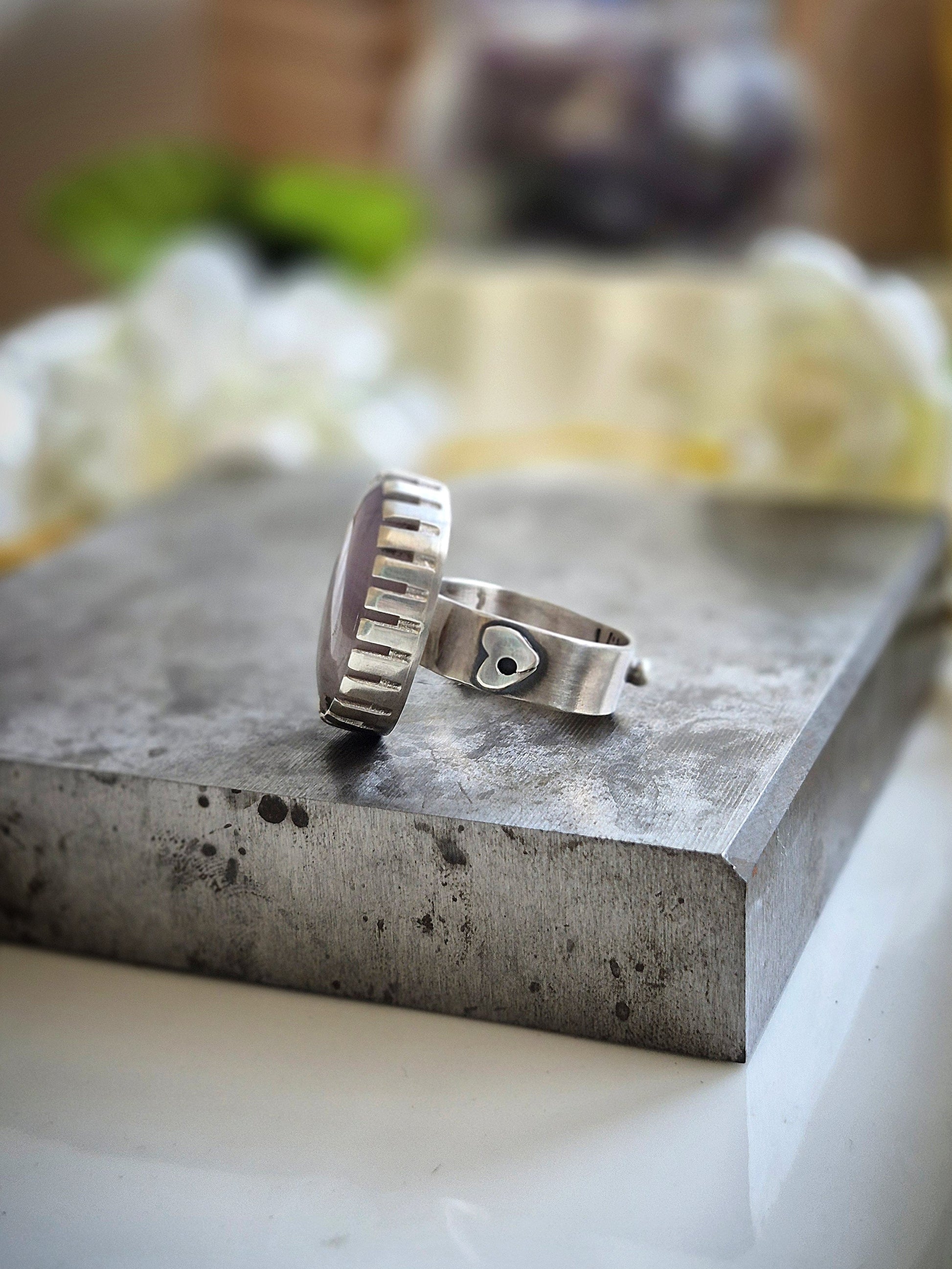 Silver ring on a textured stone surface with a blurred natural background