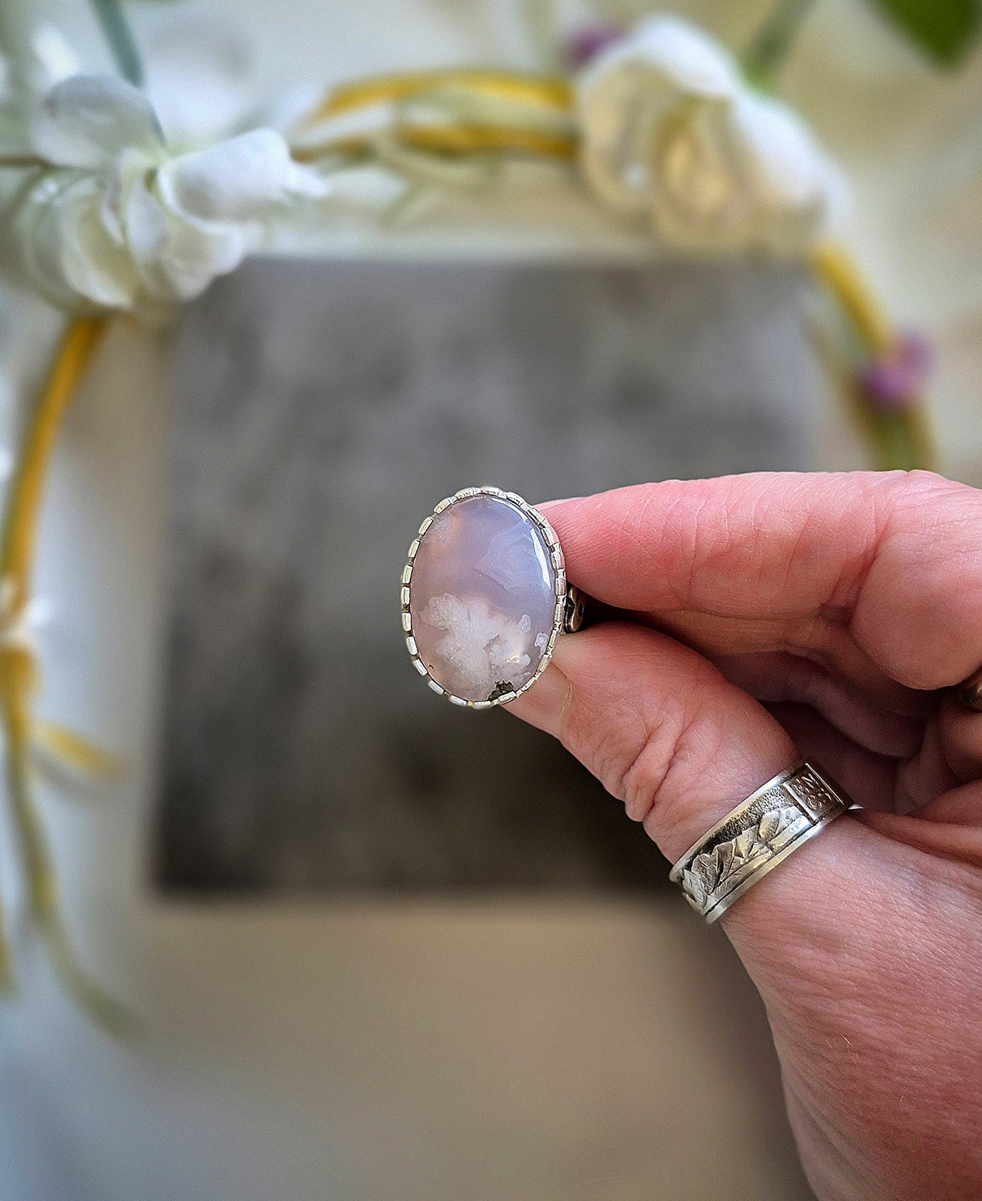 Hand holding a pinkish ring with a decorative background