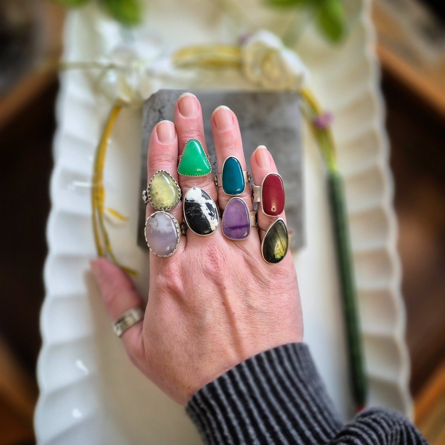 Hand wearing multiple colorful rings with a blurred background